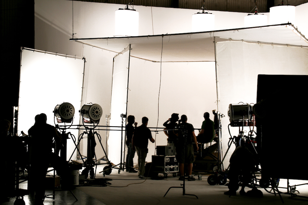 Film professionals stand, backlit, on a film set